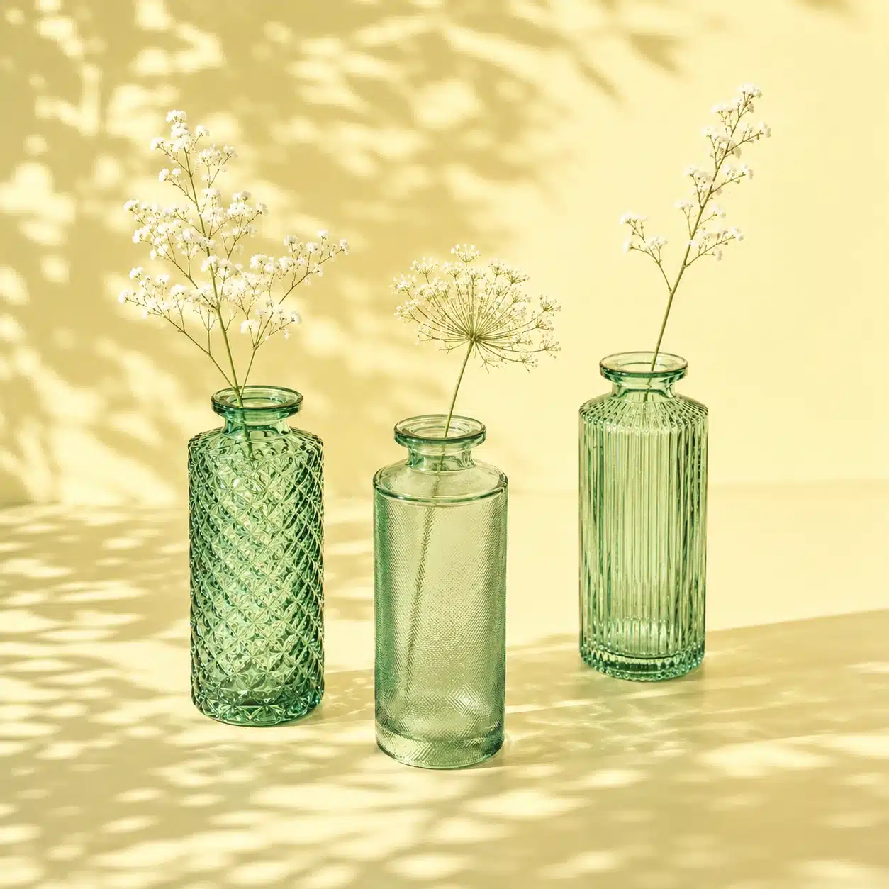 Grüne Vasen aus Glas mit filigranen weißen Blüten