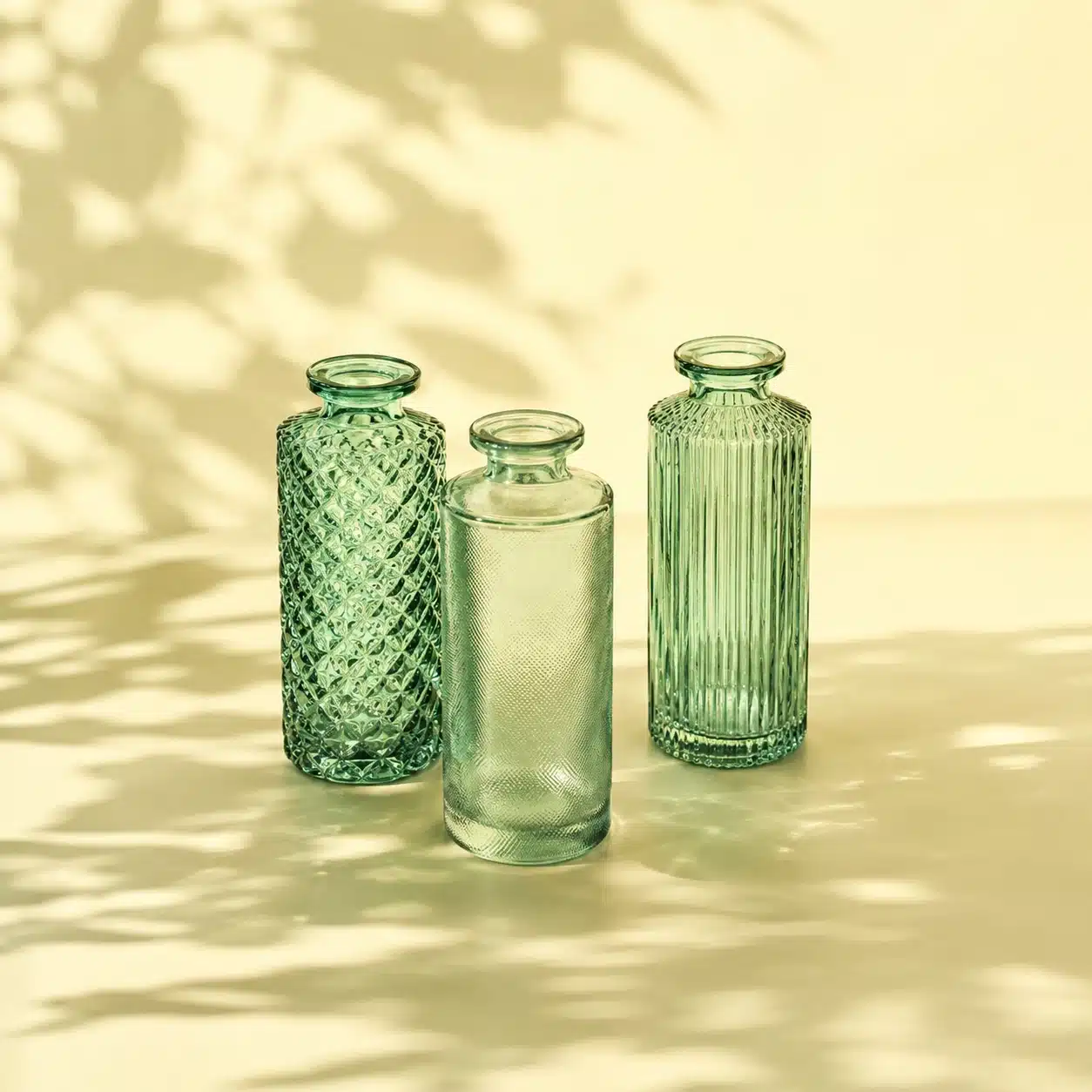 grüne vasen aus glas auf einem gelben hintergrund