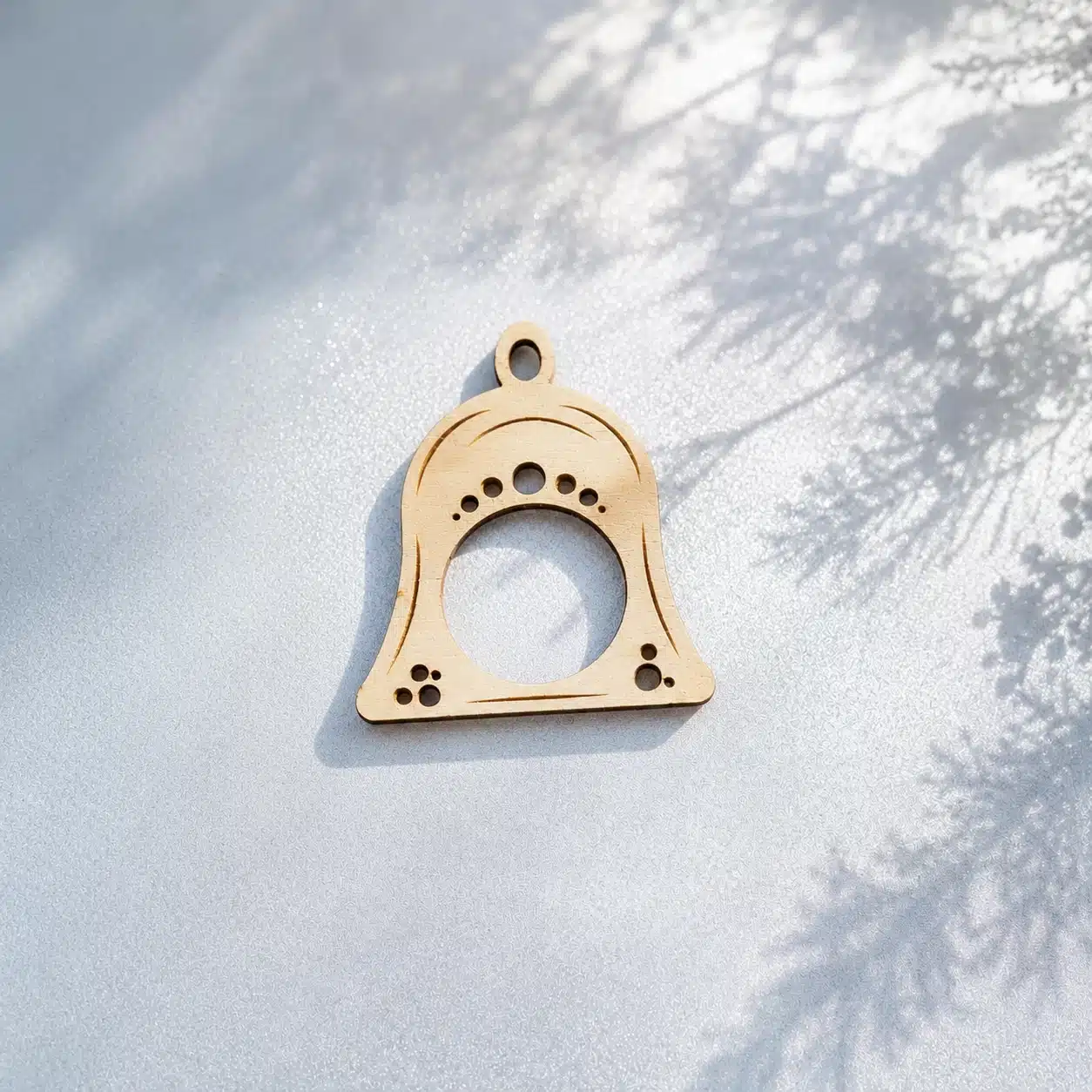 Serviettenring Weihnachtsglocke Jingle Bells aus Holz auf blau-silbernem Hintergrund mit Tannenschatten