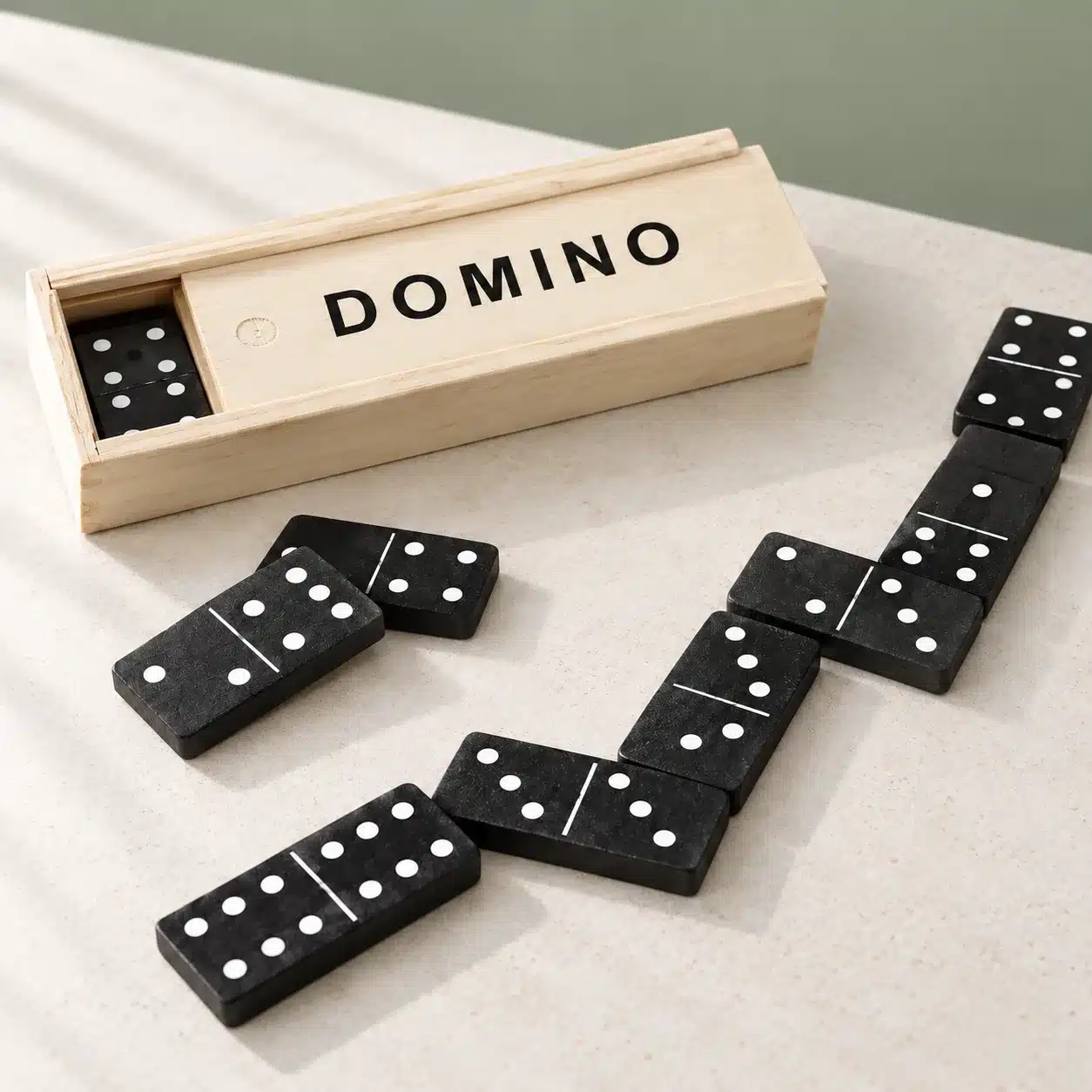 Angefangene Partie mit dem Dominospiel, daneben die geöffnete Holzkiste.